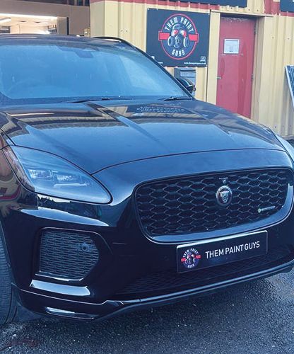 A black hybrid Jaguar F-Pace parked outside Them Paint Guys Vehicle Body Shop following minor cosmetic damage repairs