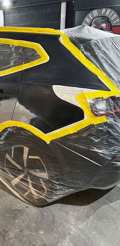 A car is encased in plastic sheeting and yellow tape whilst undergoing a major accident repair