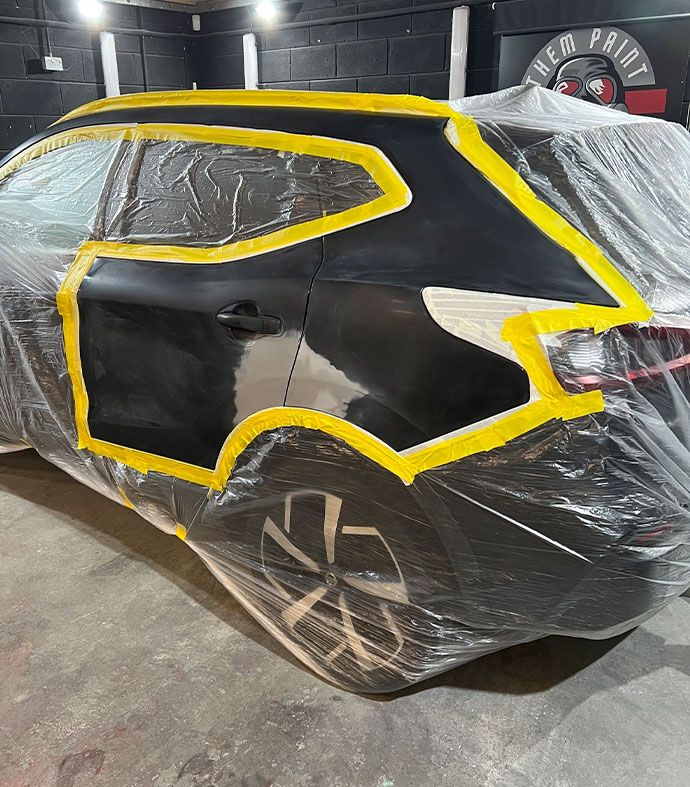 A car is encased in plastic sheeting and yellow tape whilst undergoing a major accident repair