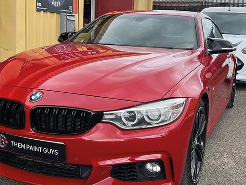 A sleek, red BMW 4 Series coupe pasked outside Them Paint Guys bodyshop looking brand new following End of Lease repairs
