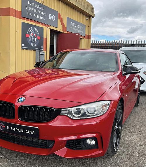 A sleek, red BMW 4 Series coupe pasked outside Them Paint Guys bodyshop looking brand new following End of Lease repairs