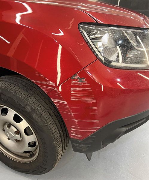 A red car with a large bumper scratch and dent on the front end ready to be SMART repaired. 