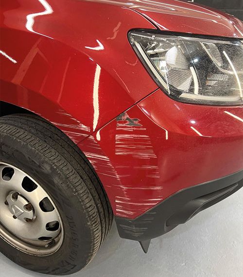A red car with a large bumper scratch and dent on the front end ready to be SMART repaired. 