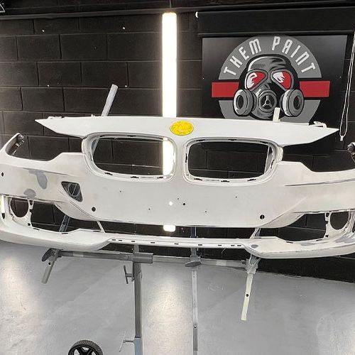 Front bumper of a BMW on a stand in the booth following damage repair and awaiting paint