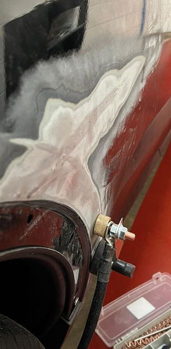 A black car being dent pulled at Them Paint Guys vehicle body shop, following damage to the wing. 