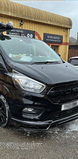 A black Ford Transit Custom parked outside Them Paint Guys Vehicle Repair Bodyshop freshly cleaned following damage repair. 