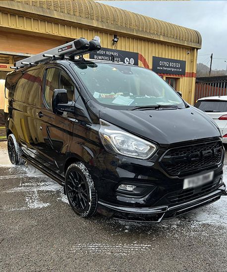 A black Ford Transit Custom parked outside Them Paint Guys Vehicle Repair Bodyshop freshly cleaned following damage repair. 